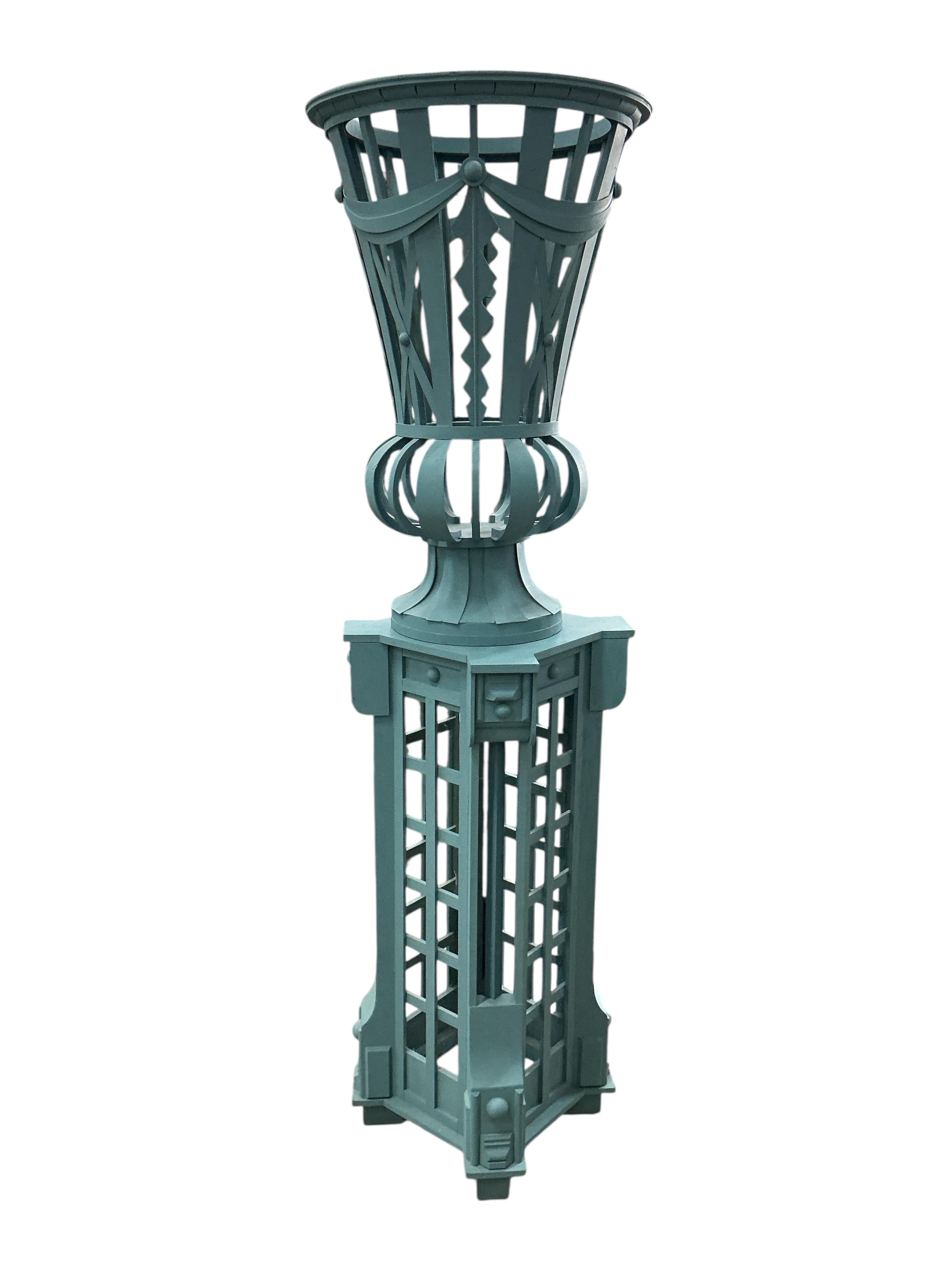 A green painted wood urn and pedestal, height 175cm, Provenance: The late Kenneth Turner (1936-2025), celebrity florist, designer and perfume retailer, he received the Royal Warrant from the Prince of Wales in the 1990s